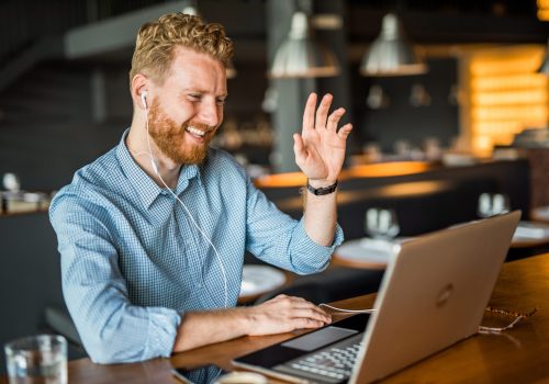 Happy young businessman waving to an online client. Happy young businessman waving to an online client.